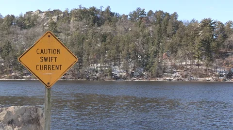 Caution Swift Current Sign with Water and Cliff in background Stock Footage 47747442