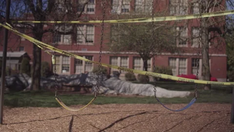 Caution tape surrounding an empty playground and school in the background Stock-Footage 130384410