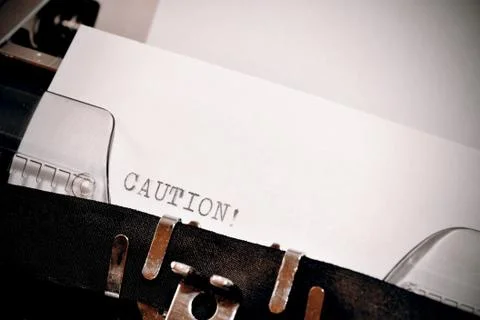 Caution text typed on old black typwriter Stock Photos