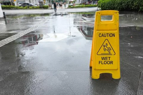 Caution Wet Floor cone in striking yellow color displayed outdoor after rain 스톡 사진