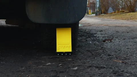 Cautionary scene: Yellow stop block placed beneath a car's tire Stock Footage 267704863