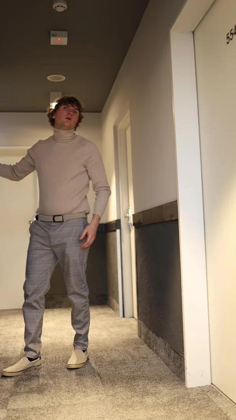 A cautious man leans slightly forward in the hallway, his body tense as he caref Stock Footage 292515848