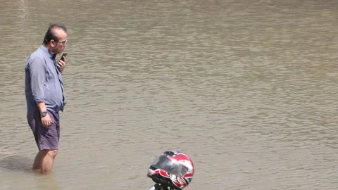 A cautious man walks slowly through a flooded street Video stock 220824628
