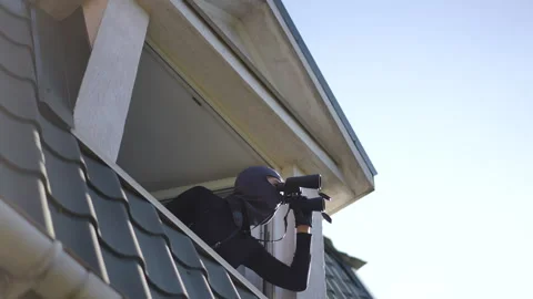 Cautiously Observing from Behind a Window, Remaining Hidden in the Shadows Stock Footage 316904932