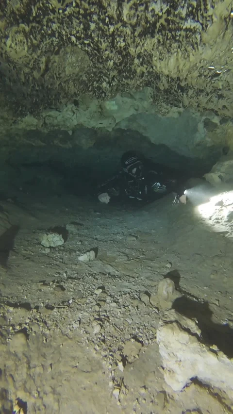 A cave diver swims through a small cave Stock Footage 277230226