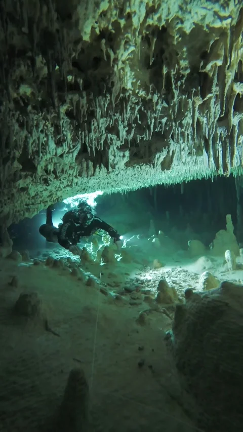 A cave diver swims through a small cave Stock Footage 277230229