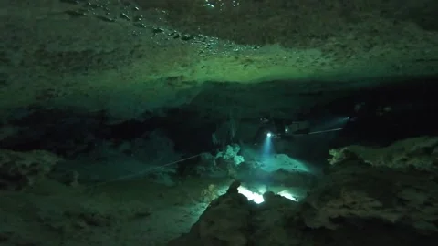 Cave divers swim through a large cavern Stock Footage 277230225
