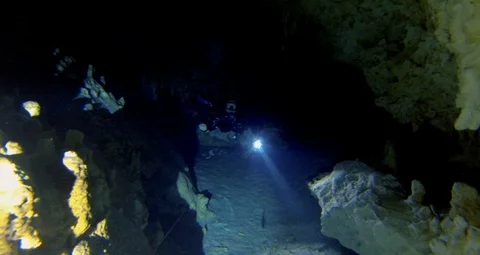 Cave diving cenote Mexico. Diver underwater in the cave shines a lantern Stock Footage 90549415