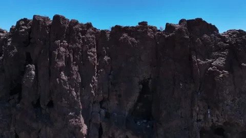 Cave-Filled Dark Mountain with Stunning Coastal Backdrop – Drone View Stock Footage 310146117