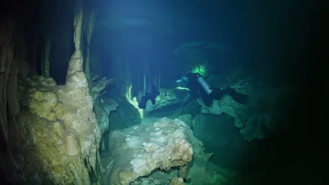 A cave with a large rock formation and a person in a green scuba suit Stock Footage 295937782