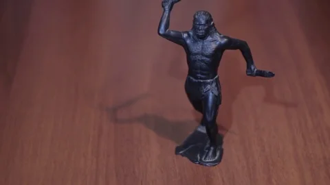 A caveman with a bat and knife in hands on dark background black toy Stock Footage 71890120