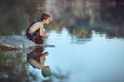 Caveman. Little boy sitting on the beach and looks at the water Stock Photos