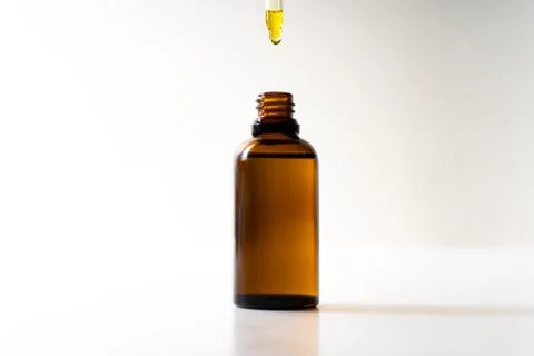CBD oil or any other oil dropping into a small bottle - white background Stock Photos