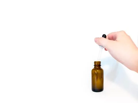 CBD tincture bottle with a hand in view, holding the dropper Stock Photos