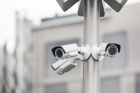 CCTV camera fixed on metal pole on city street. Close-up. Concept of security Stock Photos