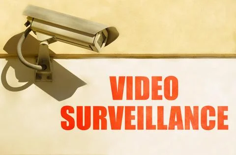 A CCTV camera is installed on the wall of the building, next to it is writt.. Stock Photos