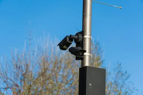 CCTV camera positioned on a sturdy pole oversees a public space, providing .. Stock Photos