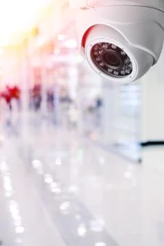Cctv camera security system on a ceiling of a shopping mall blurred background. Stock Photos