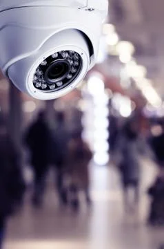 Cctv camera security system on a ceiling of a shopping mall blurred backgroun Stock Photos