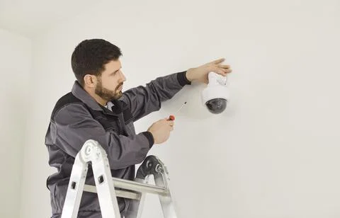 CCTV installation connecting dome security camera, male worker setting up system Stock Photos