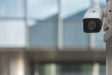 CCTV security camera on modern building wall in city Stock Photos
