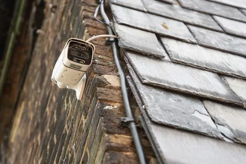 A CCTV security camera is mounted on the side wall of a residential house. Stock Photos