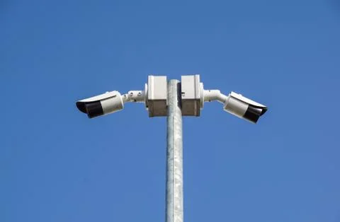 CCTV surveillance security camera on a black pole with blue sky background Stock Photos