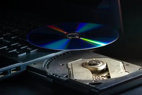 CD on the computer notebook cd rom in darkness. Stock Photos