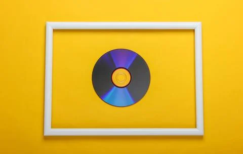 CD disk in white frame on yellow background. Top view Foto stock