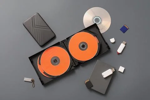 CD disks and different memory storage devices on grey background Stock Photos