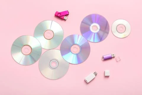 CD disks and USB flash drives on pink background Stock Photos