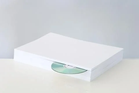 CD emerging from stack of paper 스톡 사진