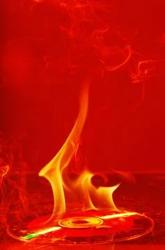 A CD or DVD disc burning in flames Stock Photos