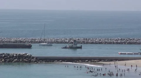 CDM beach with Tug and a loaded barge enter the harbor through rock lined jet Stock Footage 67592748