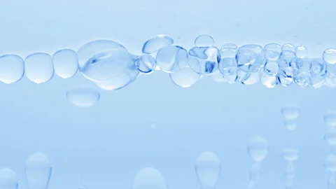 Cear bubbles form and float to another on blue liquid surface Video stock 233094417