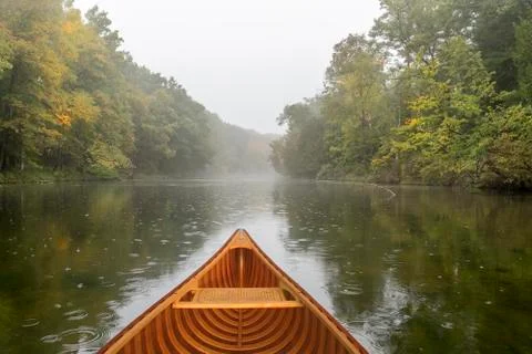 Cedar canoe on a river during a light rain Stock Photos