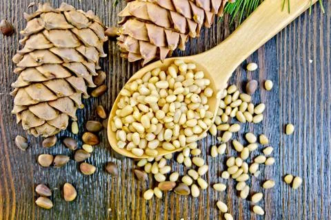 Cedar nuts refined in spoon on board Peeled kernel pine nuts in wooden spo... Foto stock