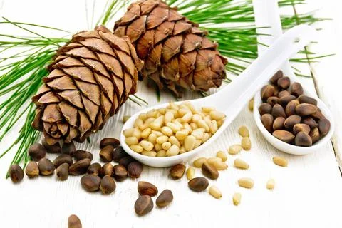 Cedar nuts in two spoons on white board Pine nuts in two spoons, two cedar... Foto stock