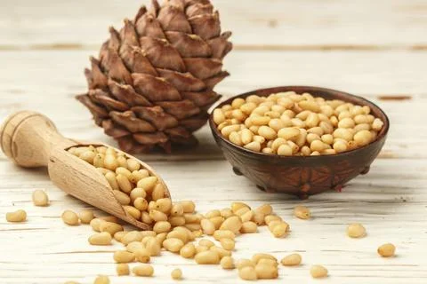 Cedar (Pine) nuts and cones on white wooden table. Selective focus Stock Photos