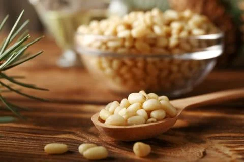 Cedar pine nuts in spoon with cones, oil, glass bowl, cedar brunch on wooden  Stock Photos