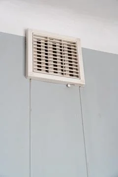 A ceiling air vent mounted on a light blue wall, providing airflow and Stock Photos