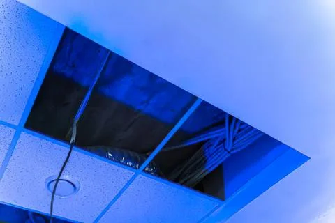 Ceiling with blue lighting and exposed wires in modern building Stock Photos