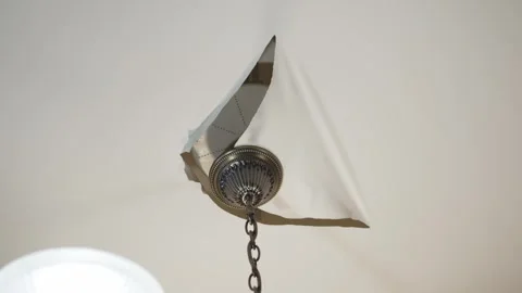 Ceiling chandelier on a torn stretch ceiling. Stock Footage 271029577