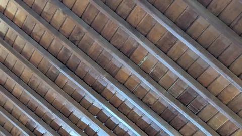 A ceiling is composed of a series of parallel wooden beams, with a tiled pa.. Stock Photos