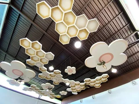 Ceiling decor featuring honeycomb and flower shapes in a modern interior space Stock Photos