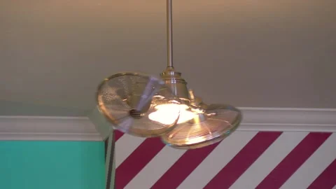 Ceiling fan lights turning in a striped room in 4k Stock Footage 281329067