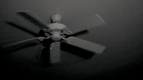 Ceiling fan rotating in dark room at night with eerie shadows. Vidéo 105200753
