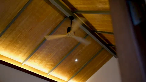 Ceiling fan spinning beneath a warm wooden ceiling in a cozy interior 스톡 동영상 341684527