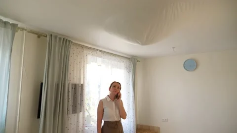 Ceiling hang down after water leak, woman stand in middle of living room Video stock 156577254