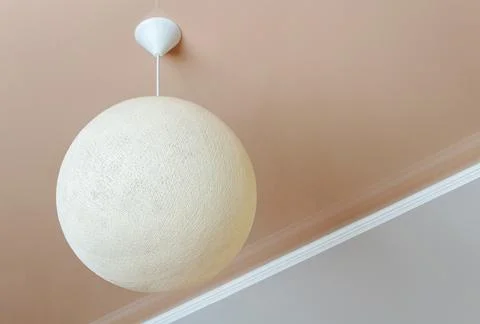 Ceiling lamp in the form of a wicker ball. Minimalist room interior. Stock Photos